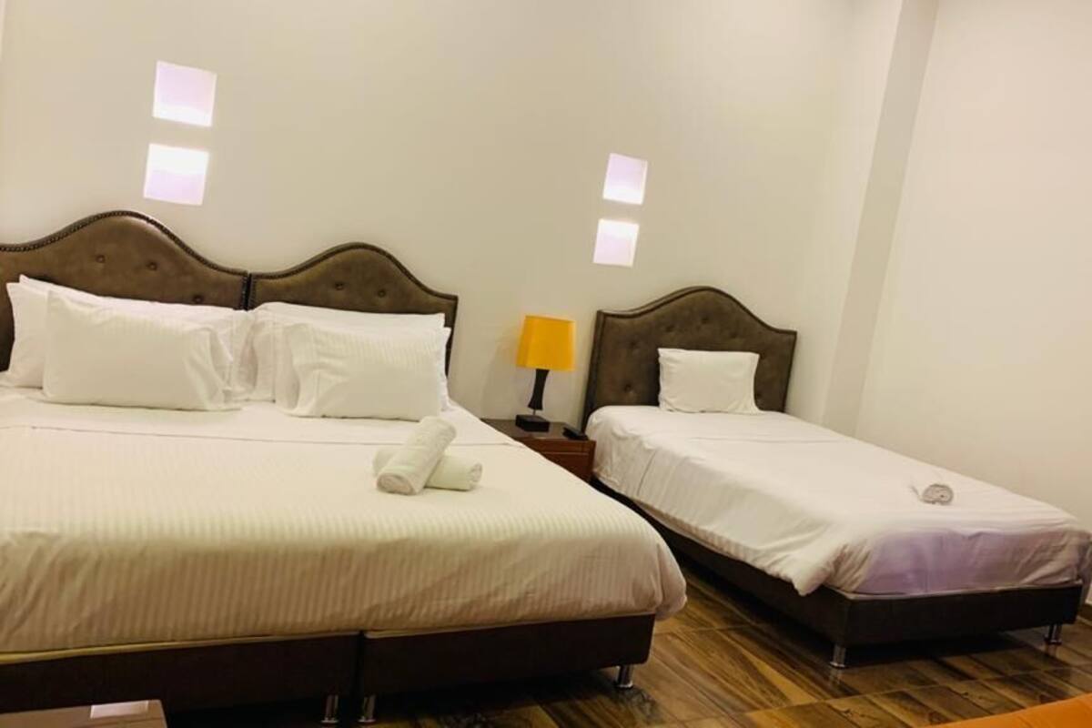 Une chambre d’hôtel avec deux lits, une table de chevet avec une lampe et un plancher en bois.