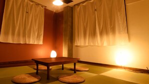 A room with tatami mats, a wooden table, and white curtains. - BACCHUS Kofu Guest House - Hostel (Kofu)