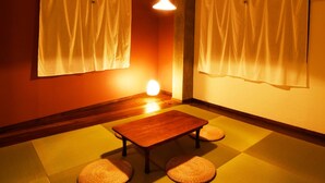A room with tatami flooring, a low wooden table, and two tatami mats as seating. - BACCHUS Kofu Guest House - Hostel (Kofu)