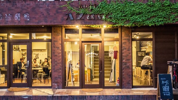 A brick building with large glass doors and windows, a sign reading "A21", and a bicycle parked outside. - BACCHUS Kofu Guest House - Hostel (Kofu)