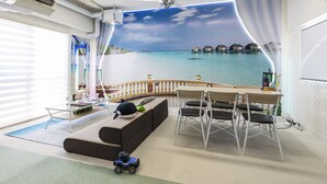 A room with a beach mural, a dining area, and a sofa. - OMOTENASHI Hostel Miyajima (Hatsukaichi)