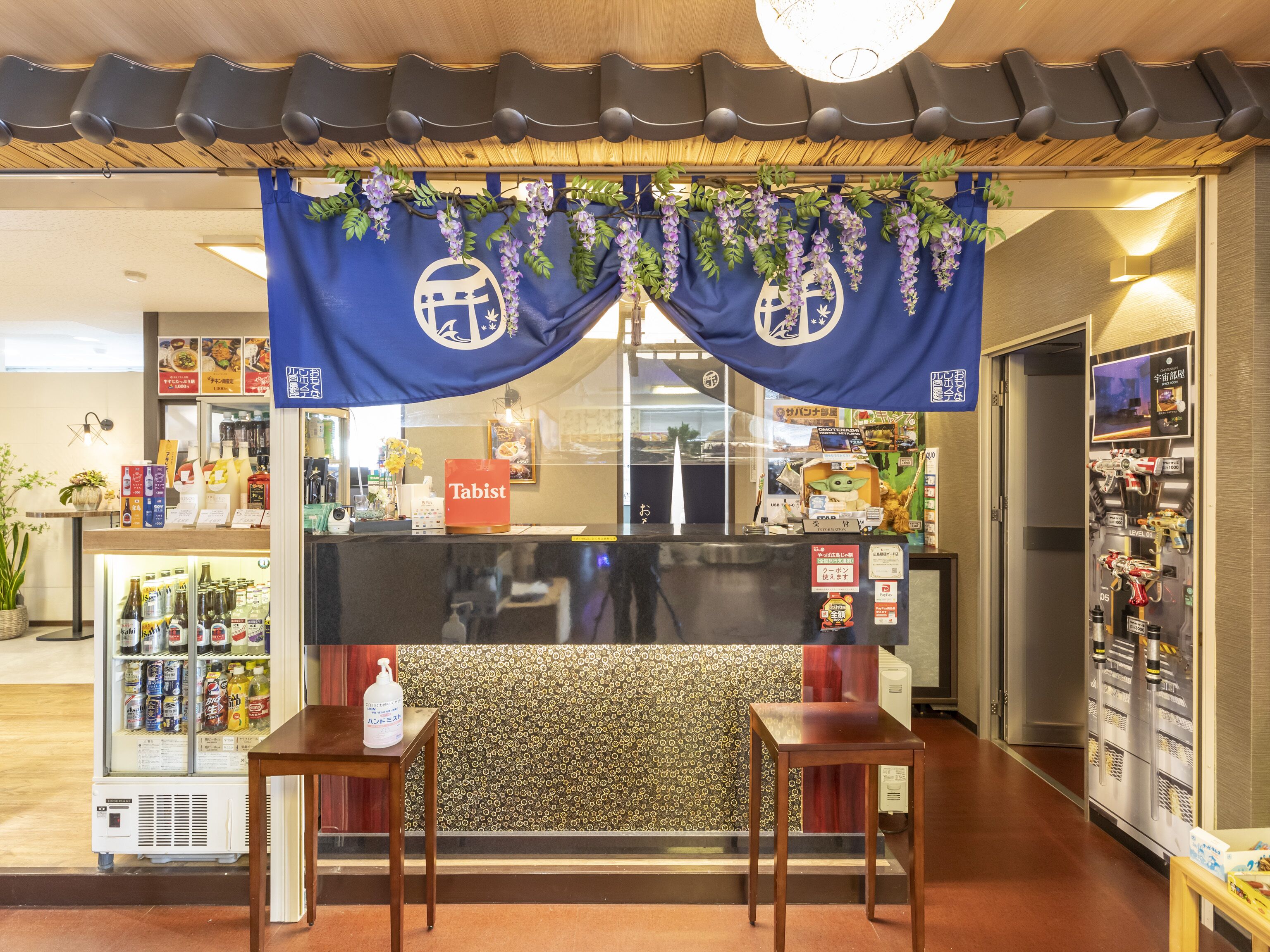 A restaurant interior with a counter, a blue decorative banner, a vending machine, and a small table.