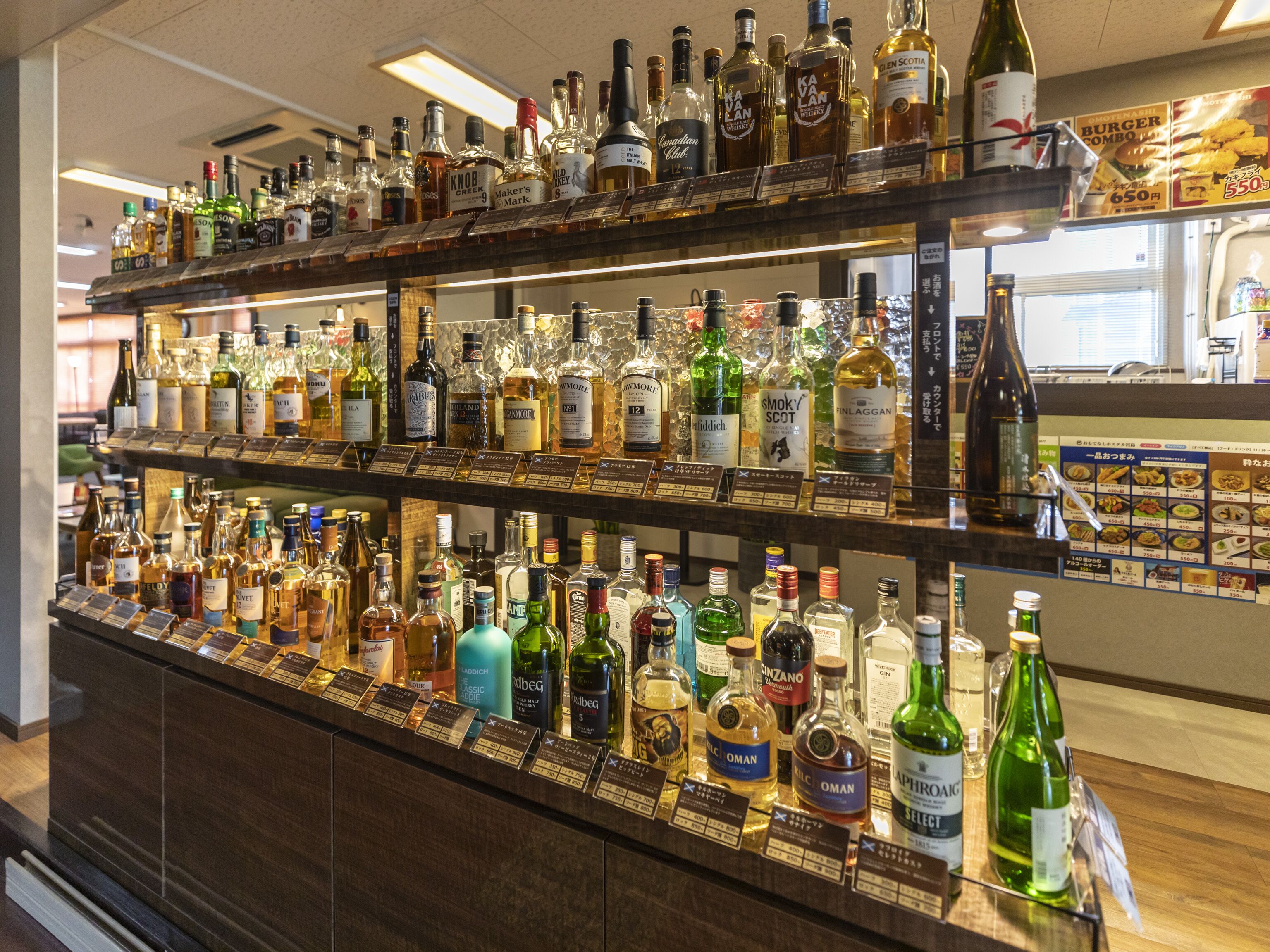 A bar with multiple shelves stocked with various liquor bottles.