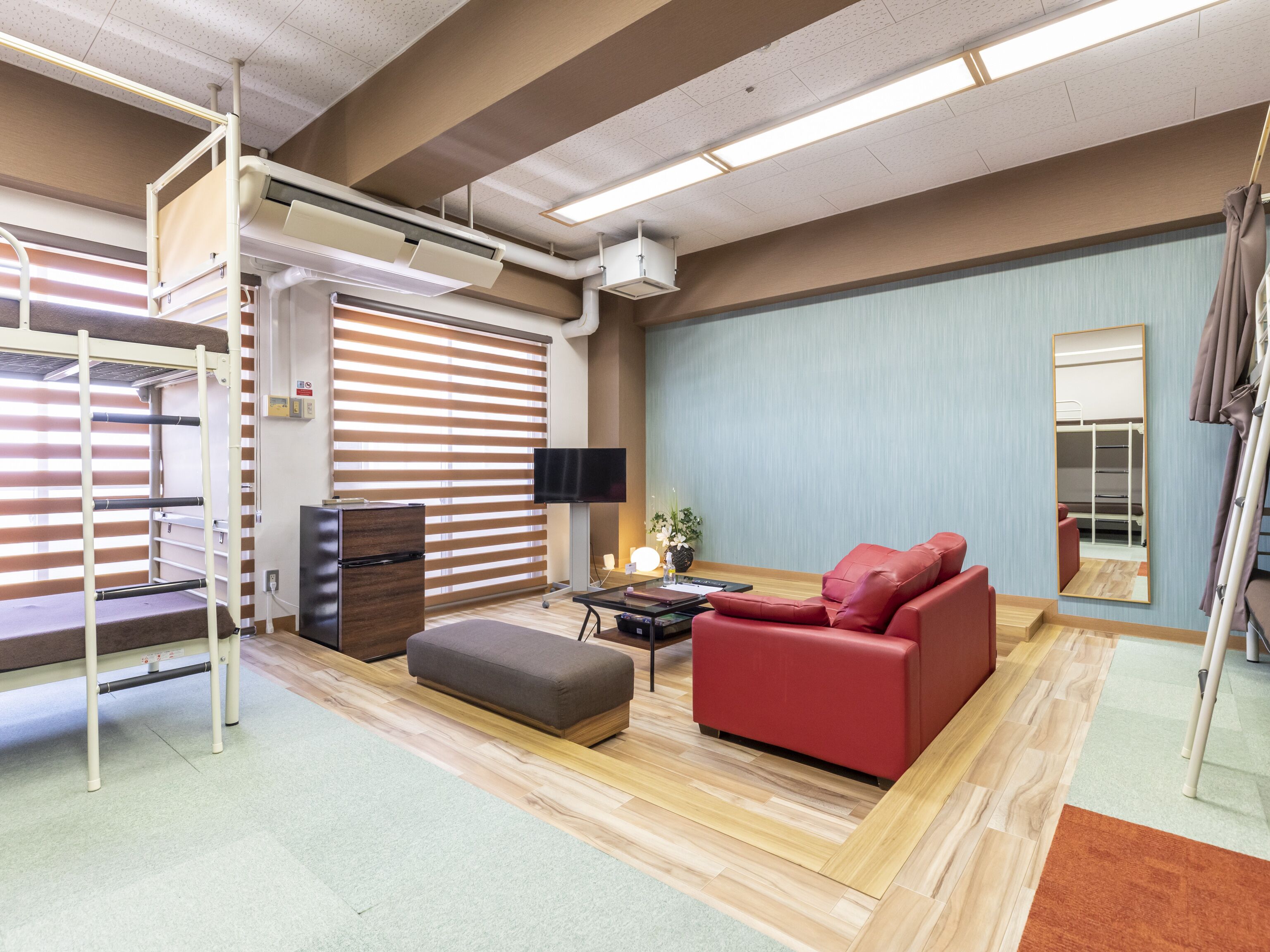 A modern room with bunk beds, a red sofa, a TV, and a mirror.