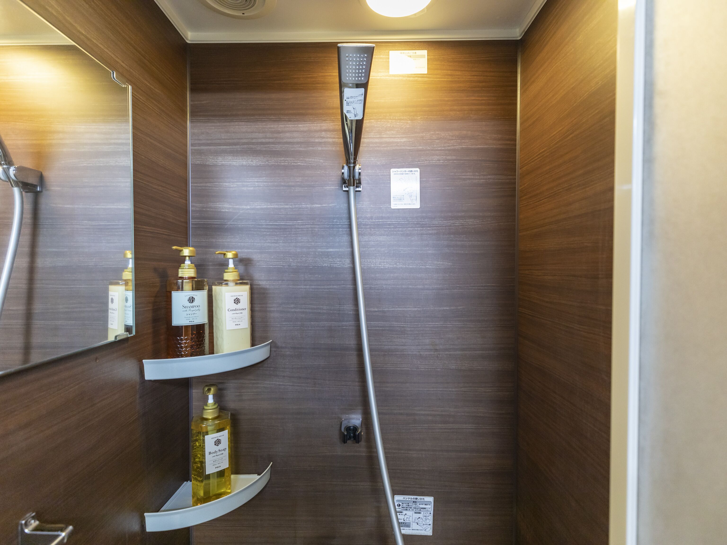 Un baño con ducha, paredes de madera y repisas con artículos de aseo.