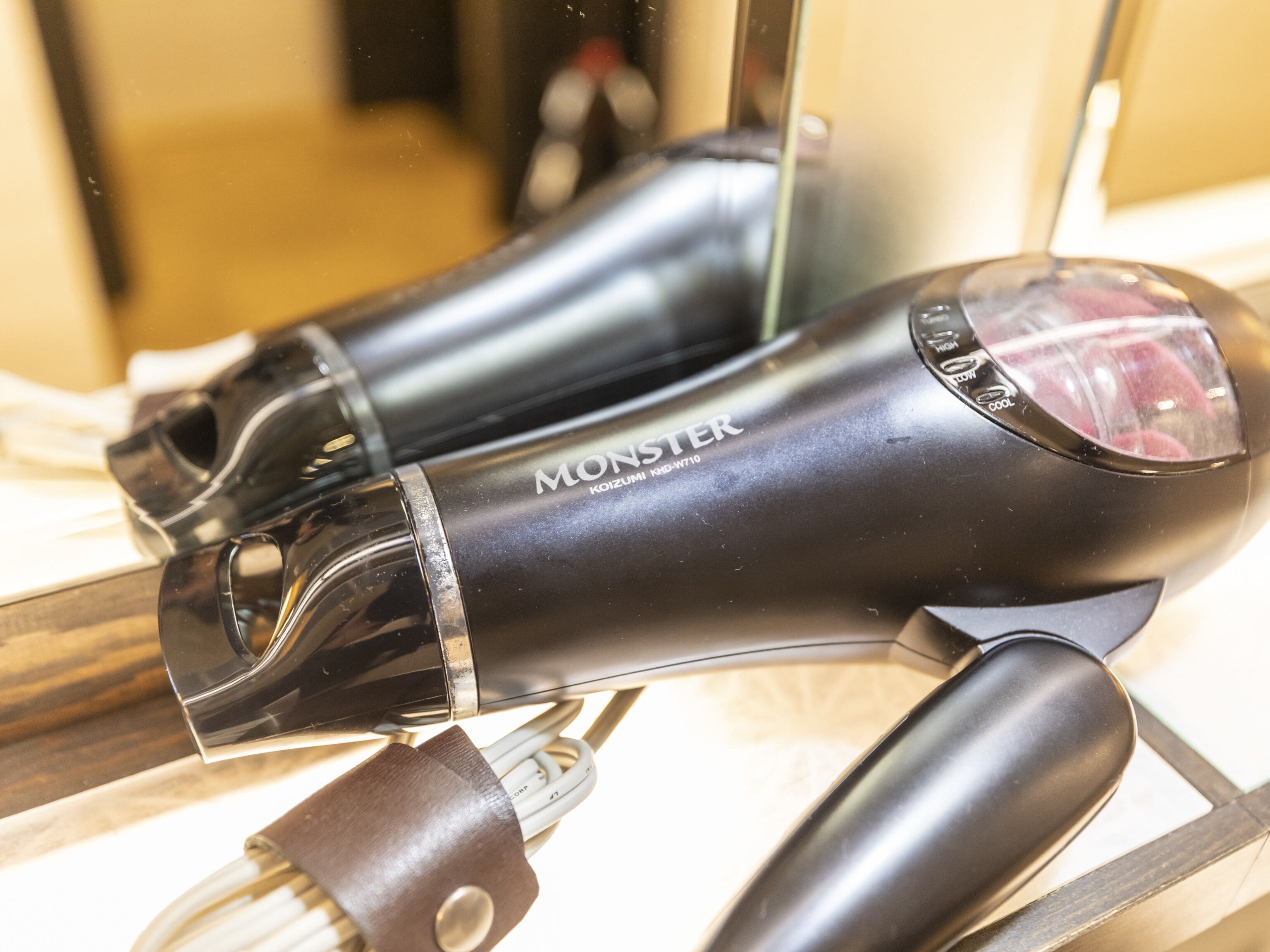 A black hairdryer with a transparent front and the brand name "MONSTER" on it.