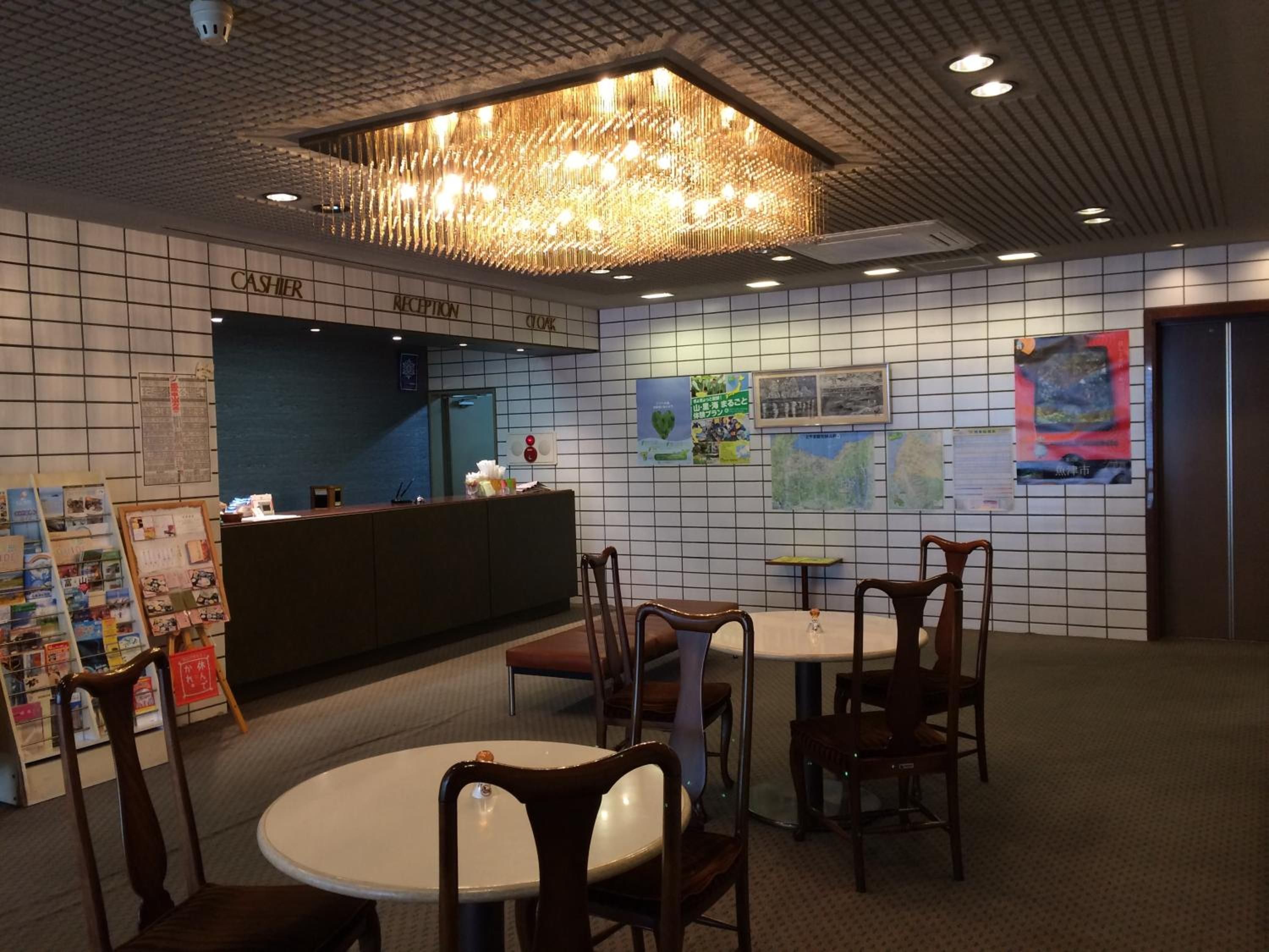A reception area with a counter, chairs, tables, and a chandelier.