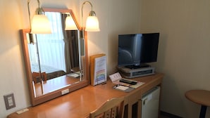 A hotel room with a wooden desk, a television, a mirror, and a small refrigerator. - Sky Hotel Uozu Annex (Uozu)