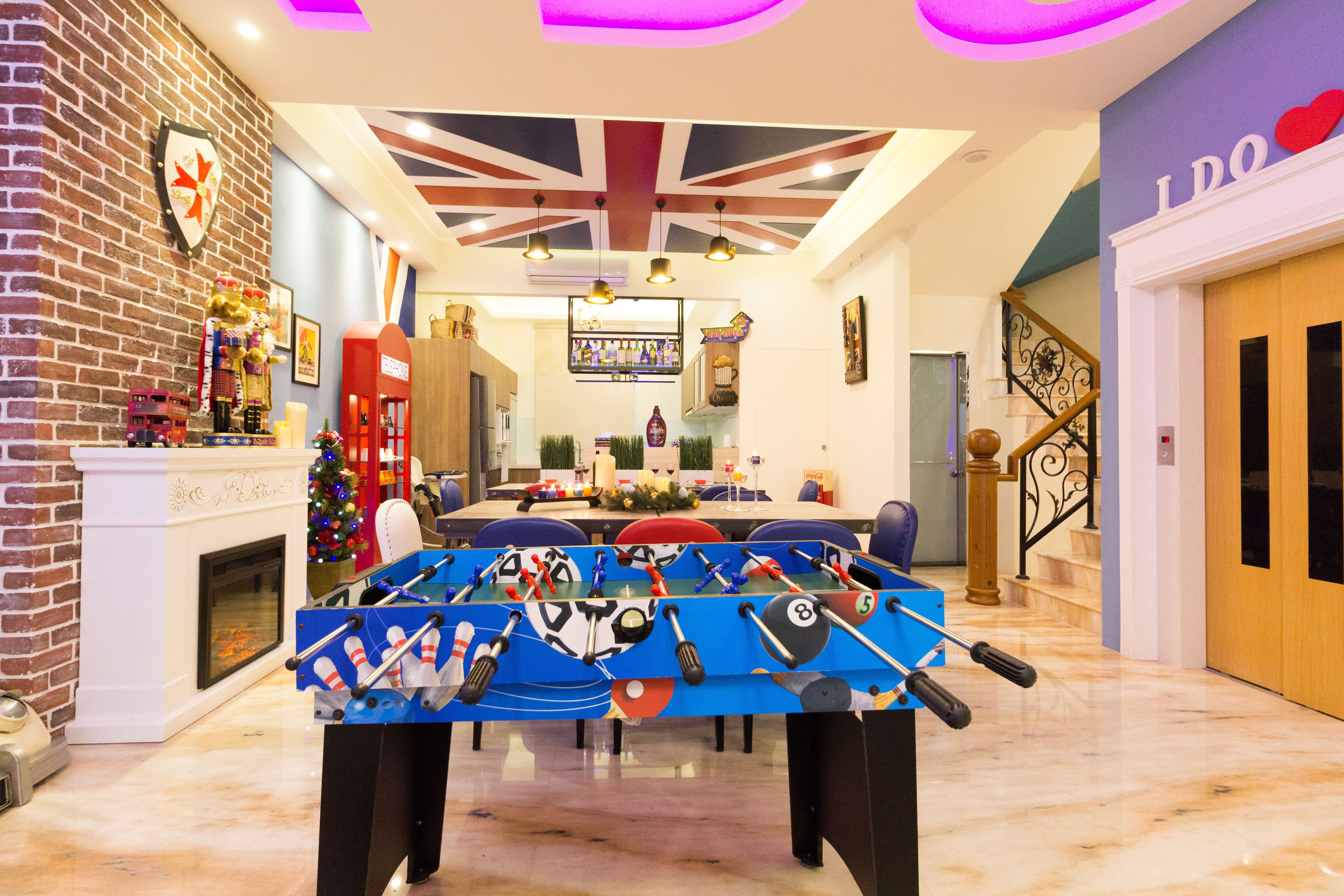 A spacious room with a foosball table, a fireplace, and a Christmas tree.