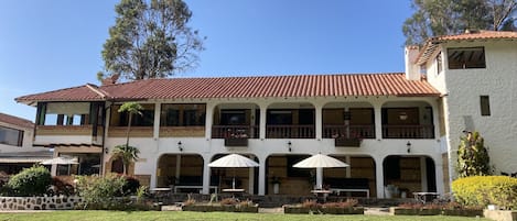 A two-story building with a tiled roof, multiple balconies, and outdoor seating areas.