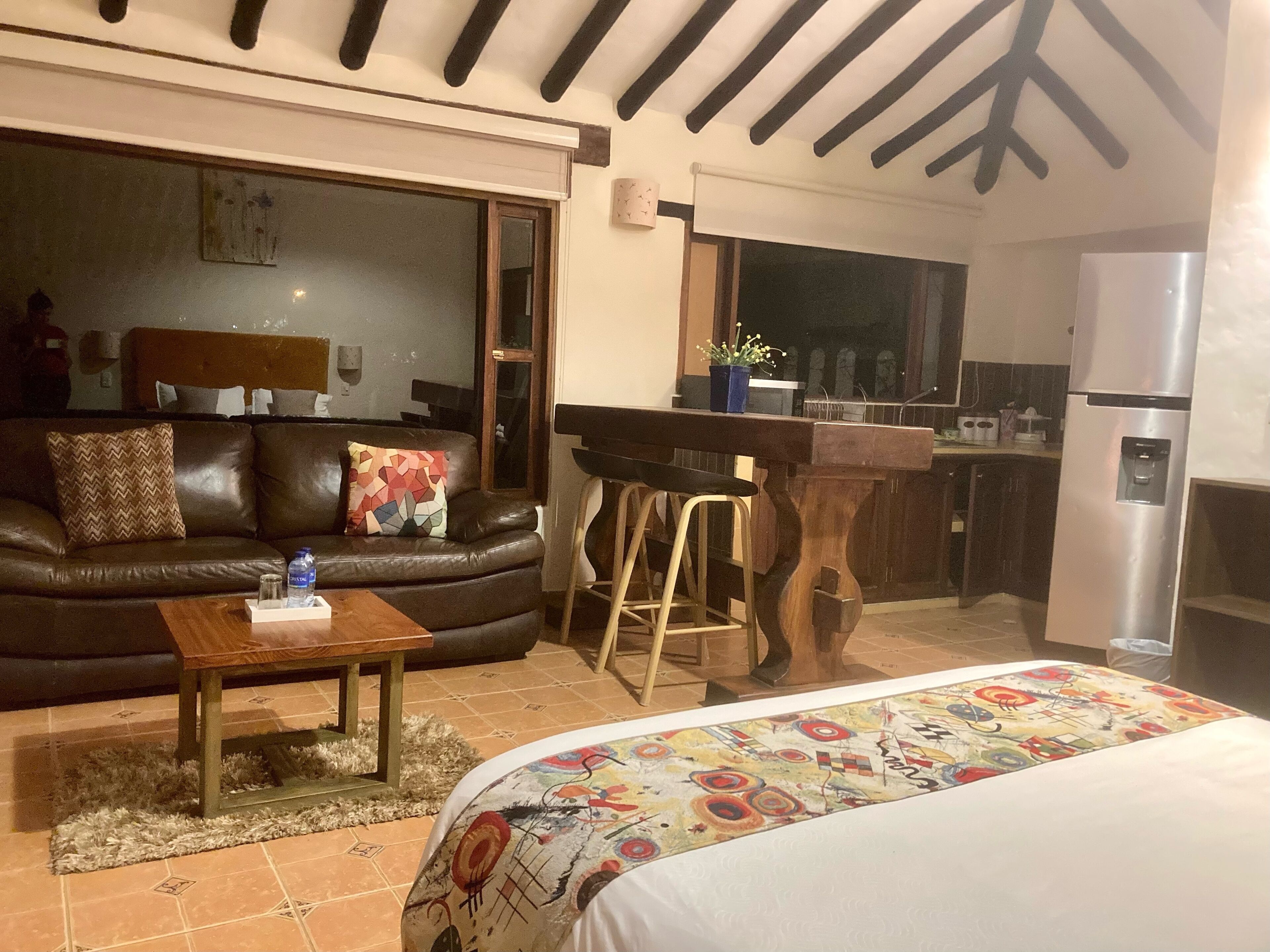 Un espacio de sala acogedor con un sofá, una mesa de centro y una colcha colorida.
