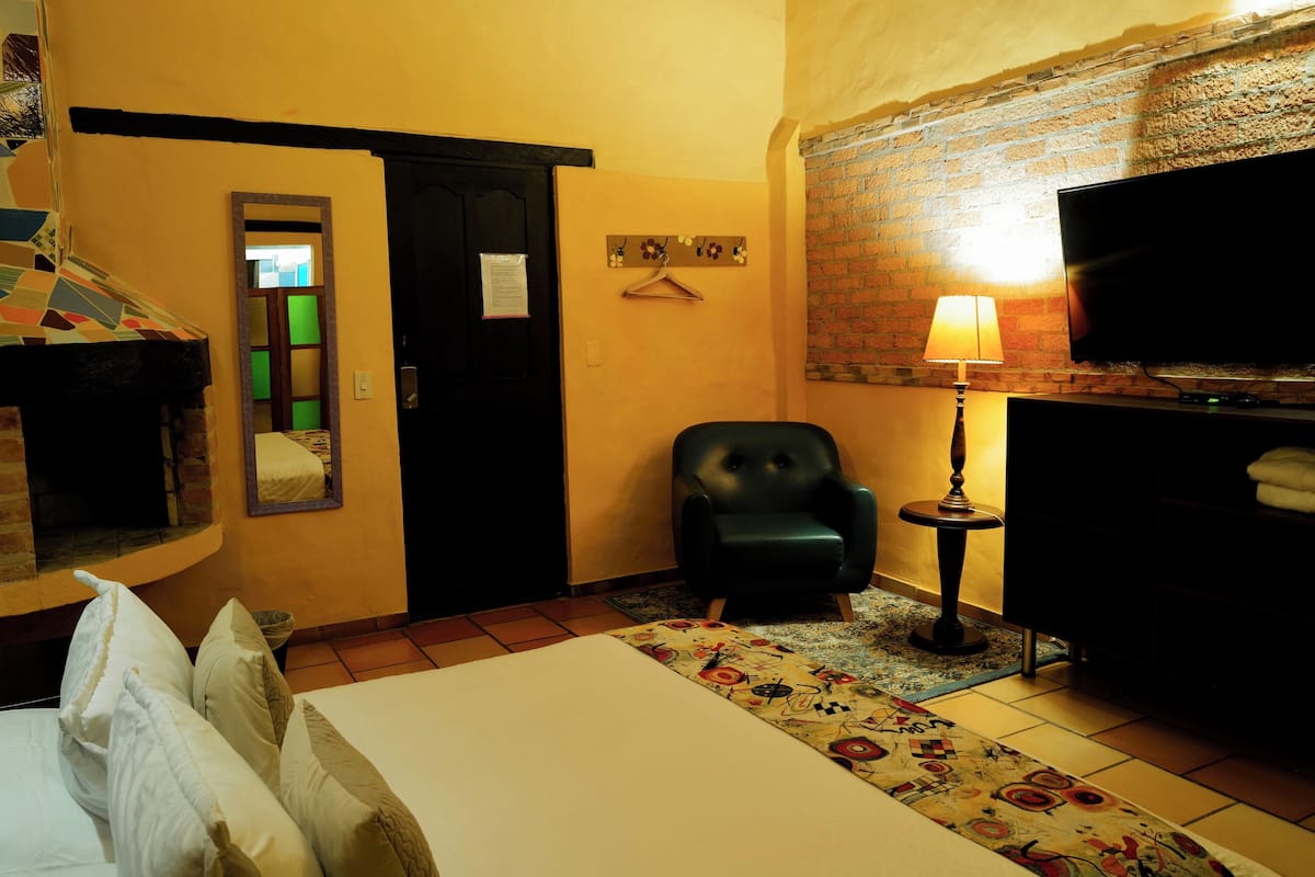 A hotel room with a bed, a chair, a TV, and a lamp.