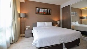 Una habitació d'hotel moderna amb un llit gran, taules de nit, una làmpada i un quadre a la paret.