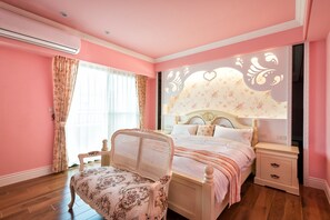 A pink-themed bedroom with a bed, a chair, a nightstand, and a decorative wall panel. - Ediman Bed and Breakfast (Hualien City)