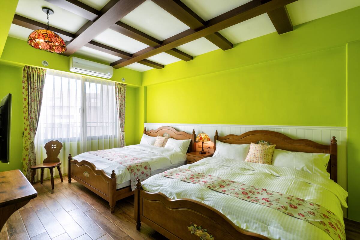 A room with two wooden beds, a wooden chair, a table, and a ceiling fan.