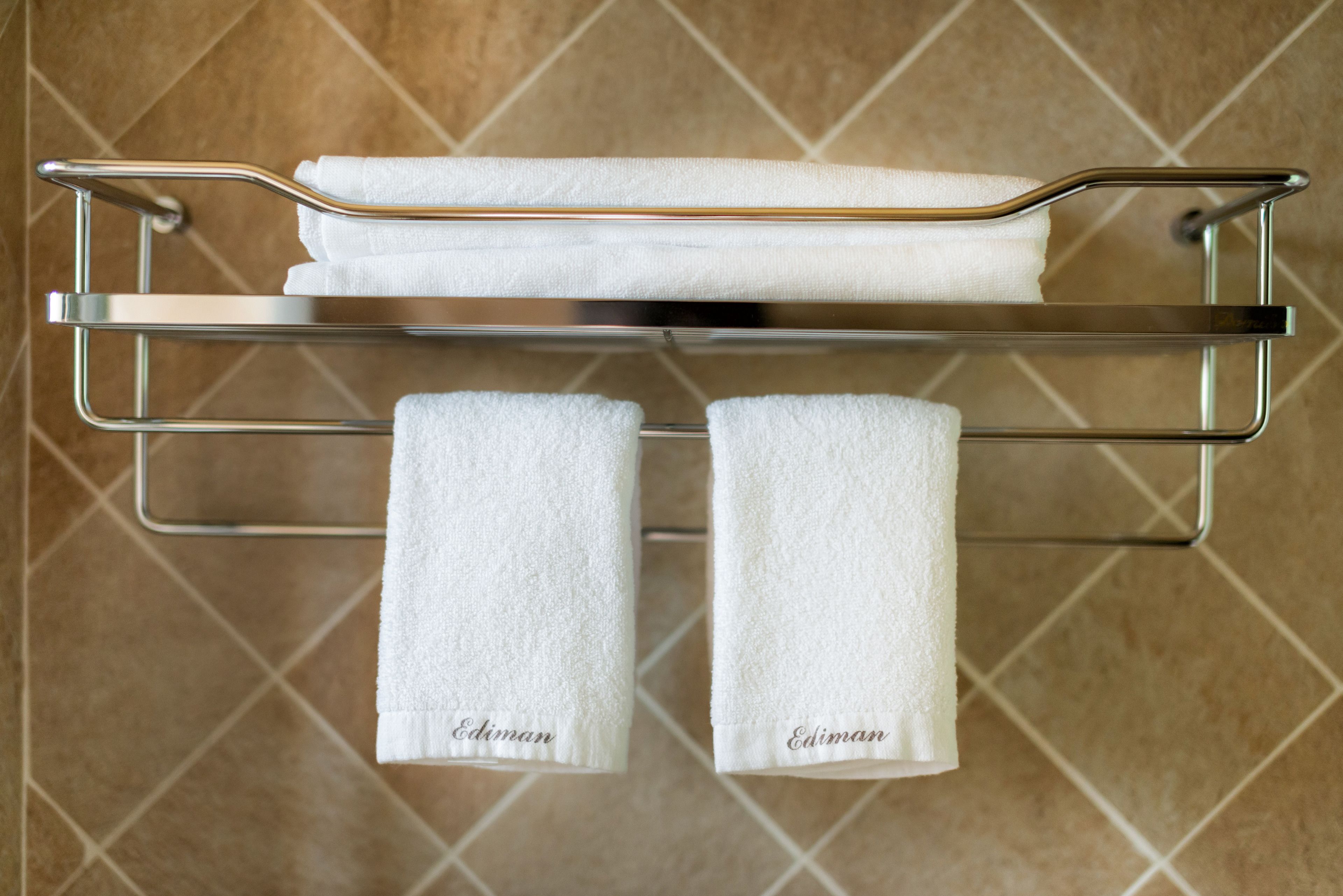A bathroom with a towel rack holding two towels labeled "Ediman."