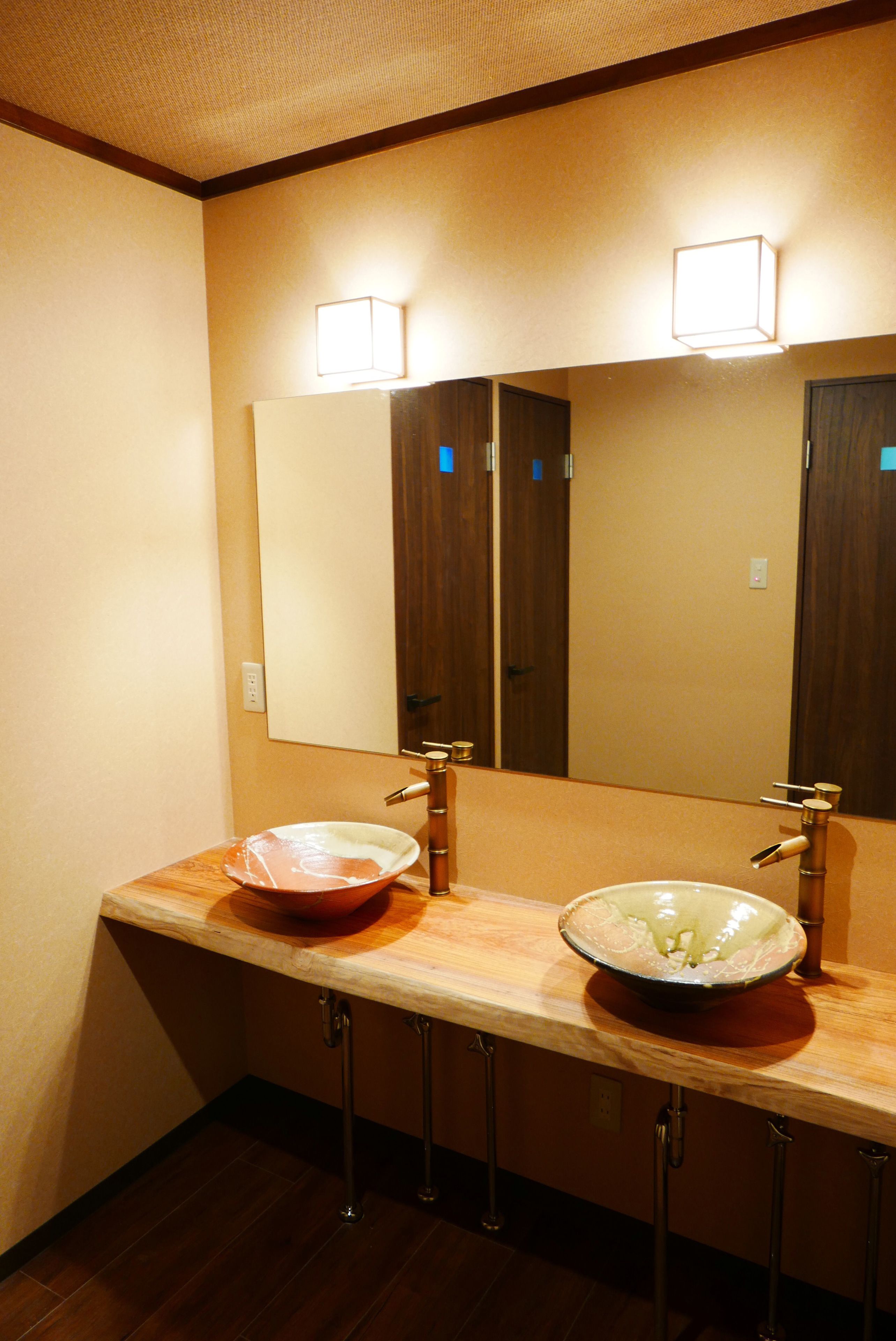 A bathroom with two sinks, a mirror, and a light fixture above the mirror.