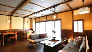 A cozy interior with a sofa, a dining table, and a hanging light fixture. - K's House Takayama Oasis - Quality Hostels (Takayama)