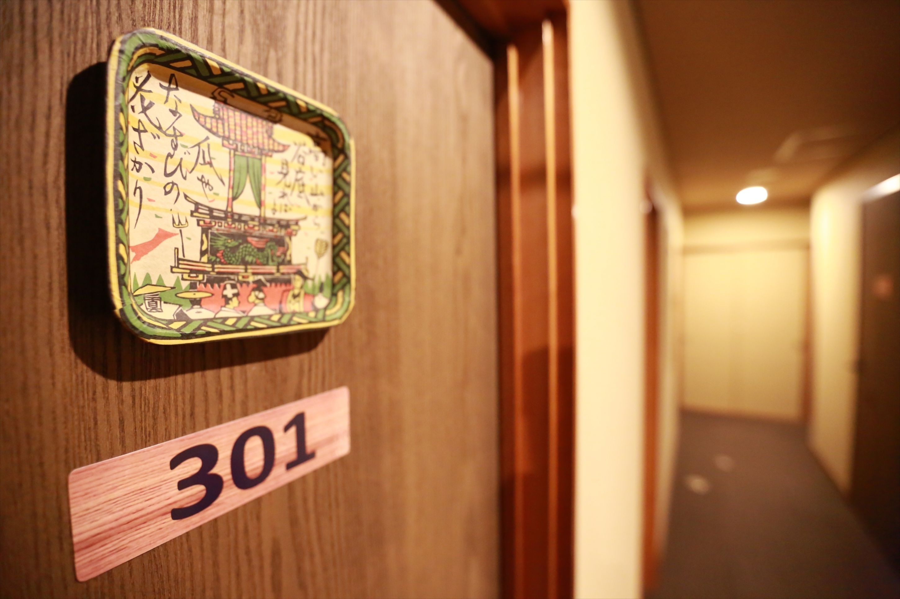 A wooden door with a room number sign '301' and a decorative plaque with Japanese characters.