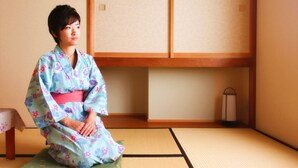 A person in a kimono sitting on a tatami mat in a room with wooden sliding doors and a small table. - K's House Takayama Oasis - Quality Hostels (Takayama)