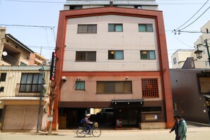 Ein mehrstöckiges Gebäude mit roter und beiger Fassade, einem verschlossenen Eingang und einem sichtbaren Schild.