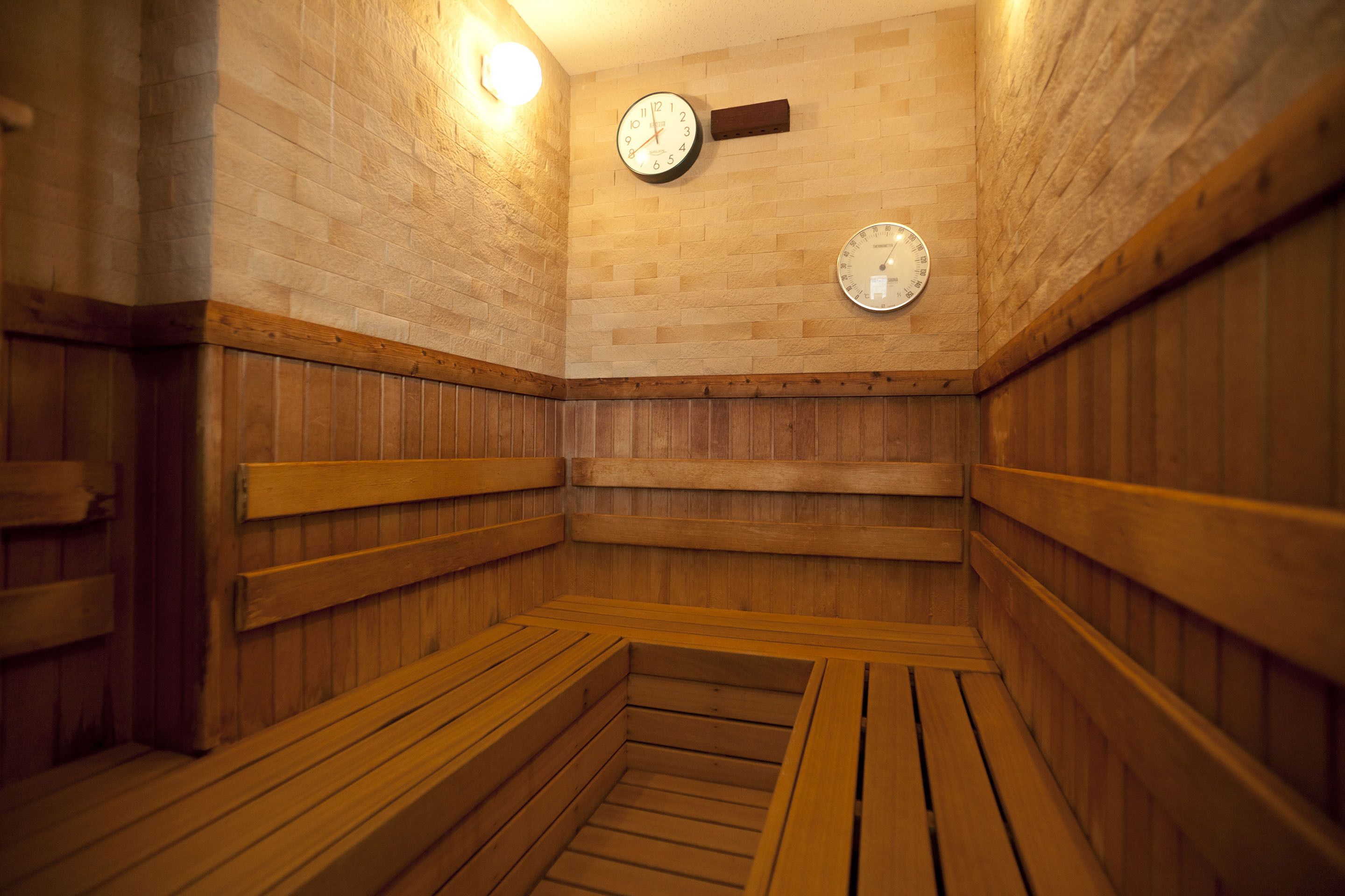 Un cuarto de sauna con bancos de madera, un reloj en la pared y techo de madera.