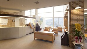 Un espace d’accueil comprenant un comptoir de réception, un coin salon et une grande fenêtre donnant sur les montagnes.