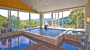 Une piscine intérieure moderne offrant une vue sur des montagnes et des arbres luxuriants.