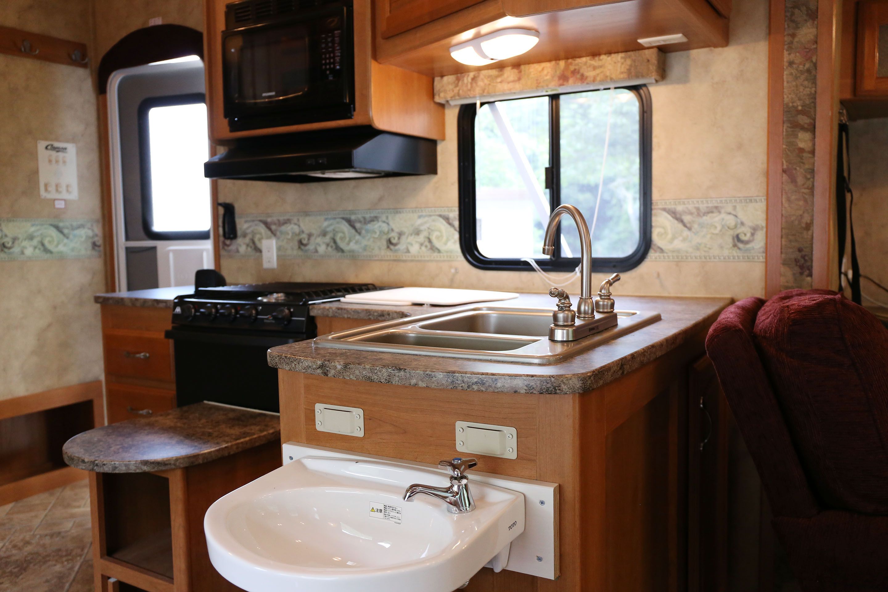 Una cocina compacta para vehículos recreativos, con un fregadero, estufa y microondas.