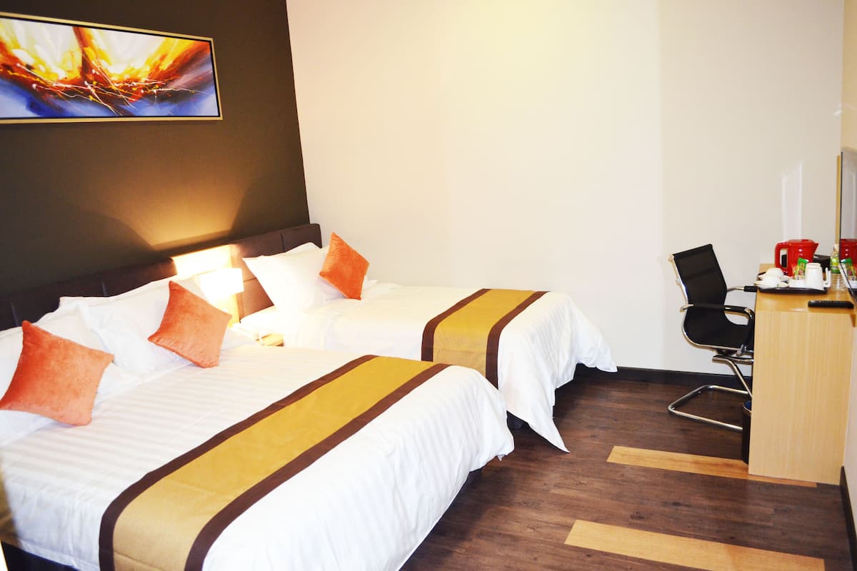 A hotel room with two beds, a desk, and a chair.