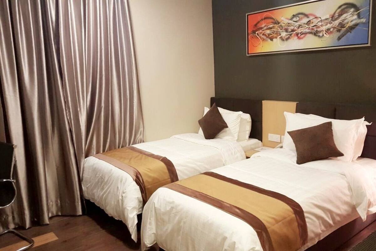 A hotel room with two beds, a painting on the wall, and a chair.