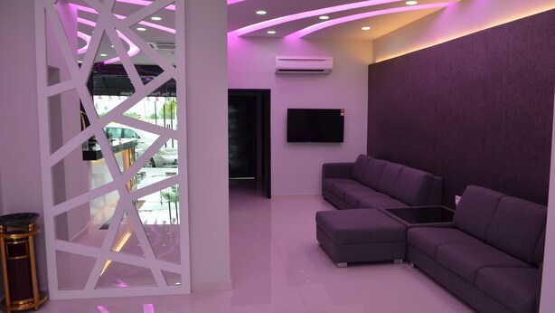 A modern interior with a sectional sofa, a glass partition, and a flat-screen TV mounted on the wall.