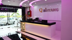 A modern reception area with a curved counter, a Q BINTANG sign, and a glass door leading outside.
