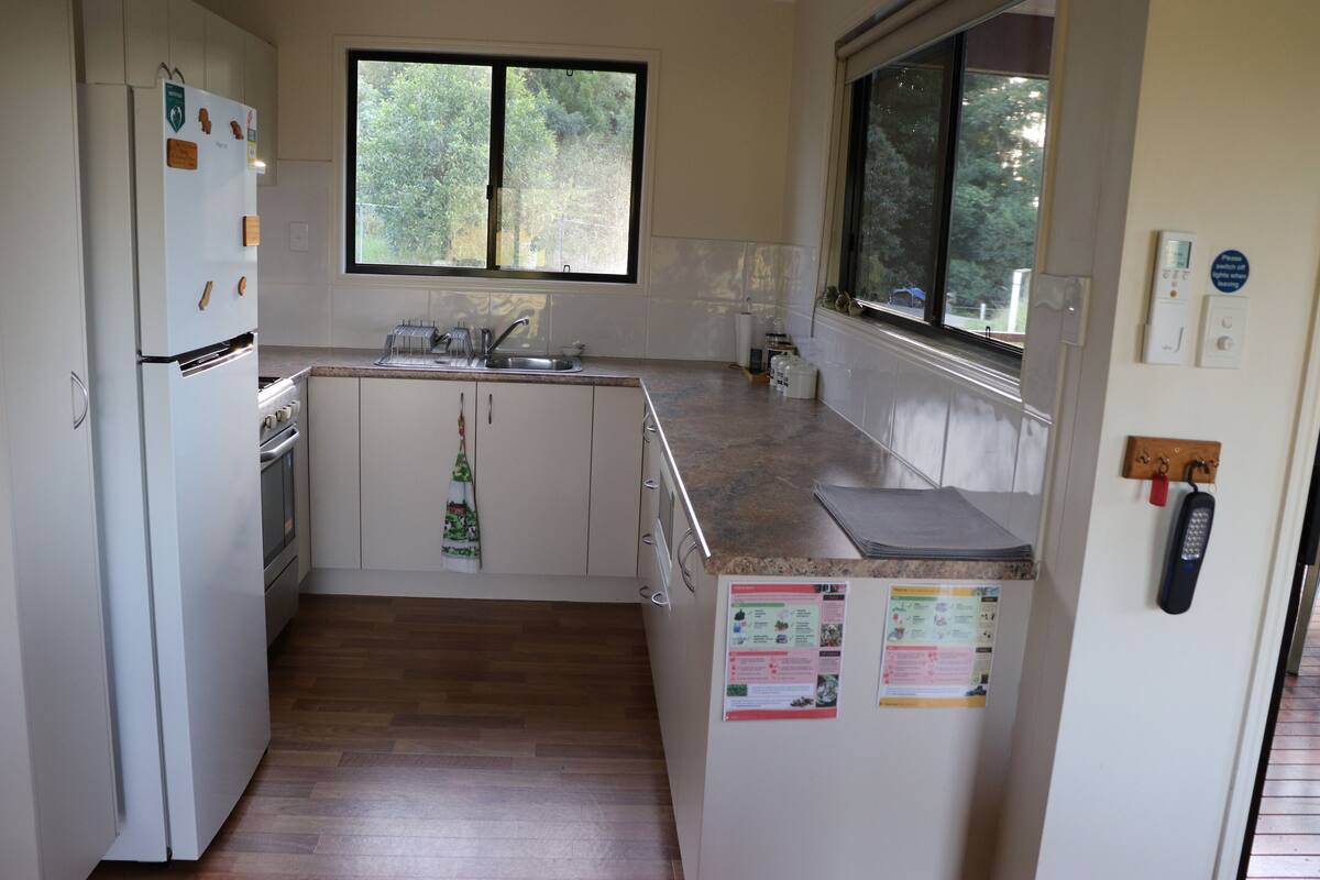 A compact kitchen with a built-in oven, a sink, and a window above the countertop.