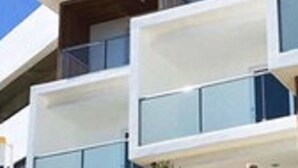 A modern multi-story building with balconies and large windows.