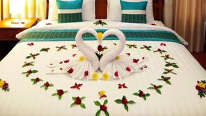 A hotel room with a wooden headboard, a bed with white and teal bedding, and a decorative swan made of fabric on the bed. - Kaya Mani Thai Villa Resort Samui (Koh Samui)