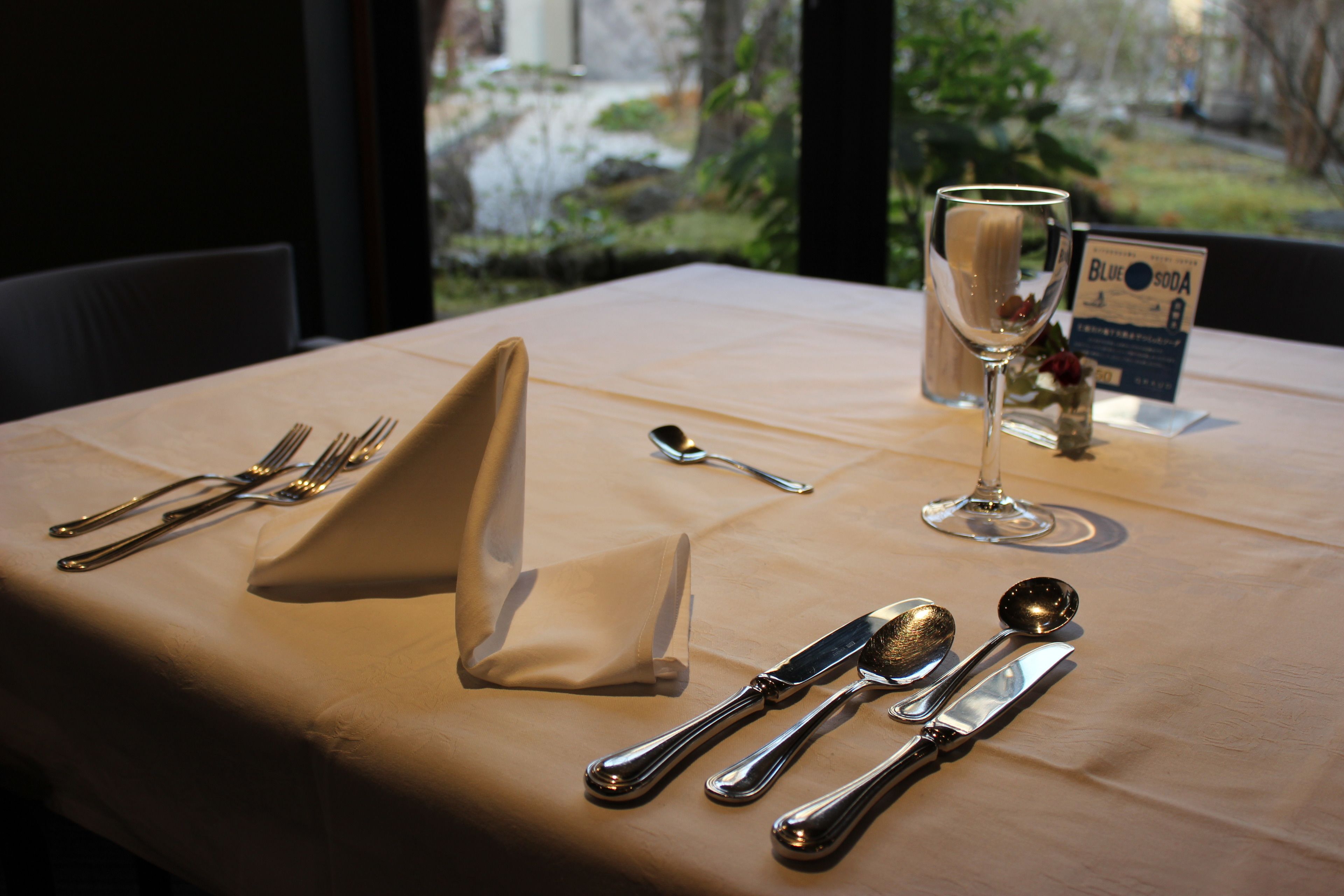 A table set for dining with cutlery, a glass, and a menu.