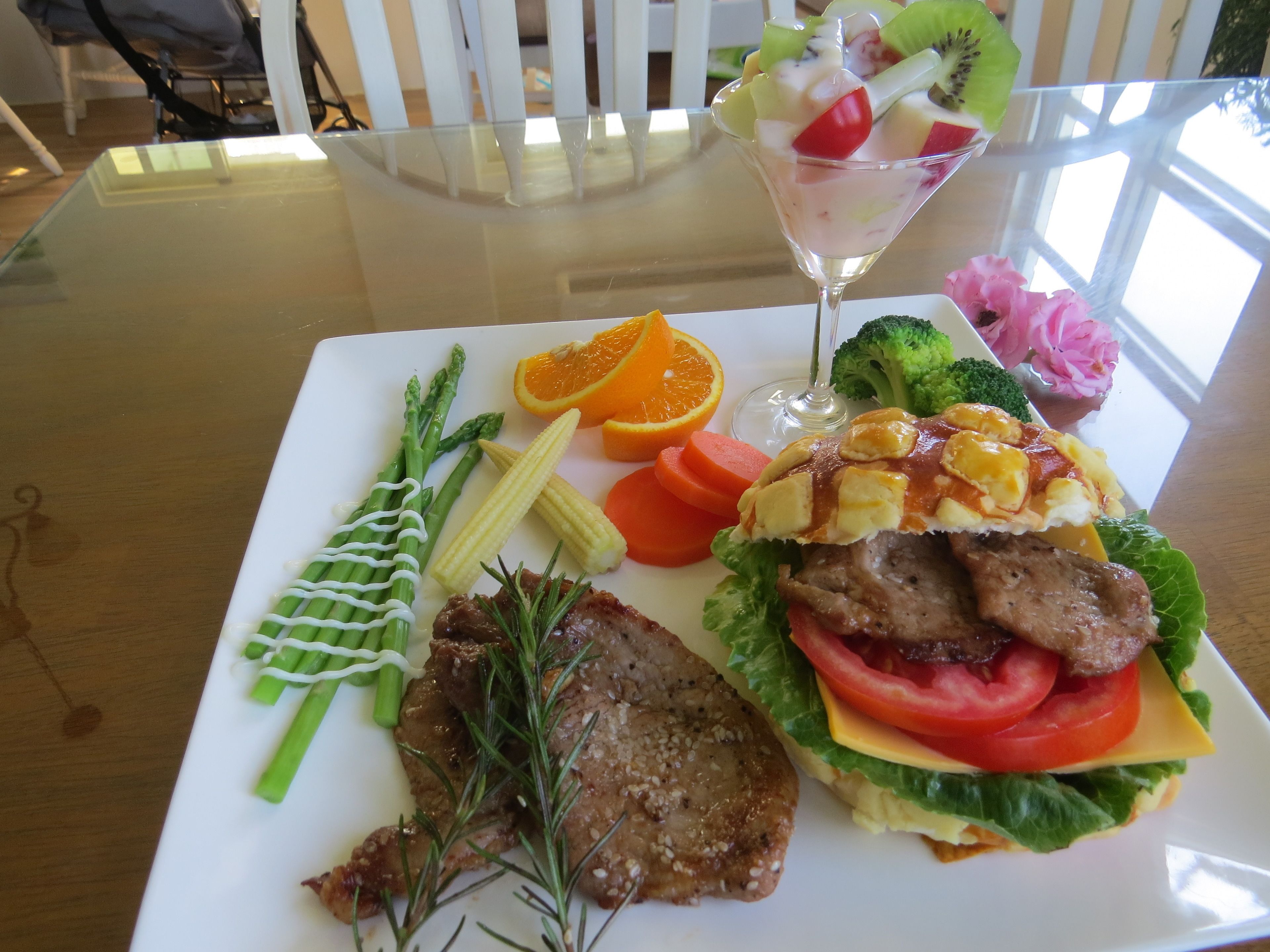 A meal with steak, vegetables, and a fruit salad on a white plate.