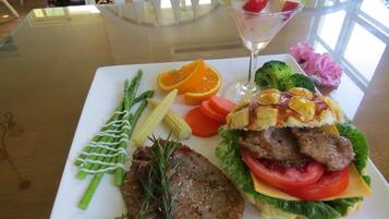 A meal with steak, vegetables, and a fruit salad on a white plate.