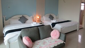 A hotel room with two beds, a nightstand with a lamp, a sofa with decorative pillows, and an air conditioning unit on the wall. - GoodEatting (Jiaoxi)