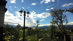 Un lampione in un giardino con vista sulle montagne e cielo sereno.