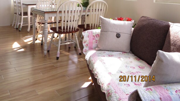 A dining area with white chairs and a table, a sofa with floral cushions, and a painting on the wall. - GoodEatting (Jiaoxi)