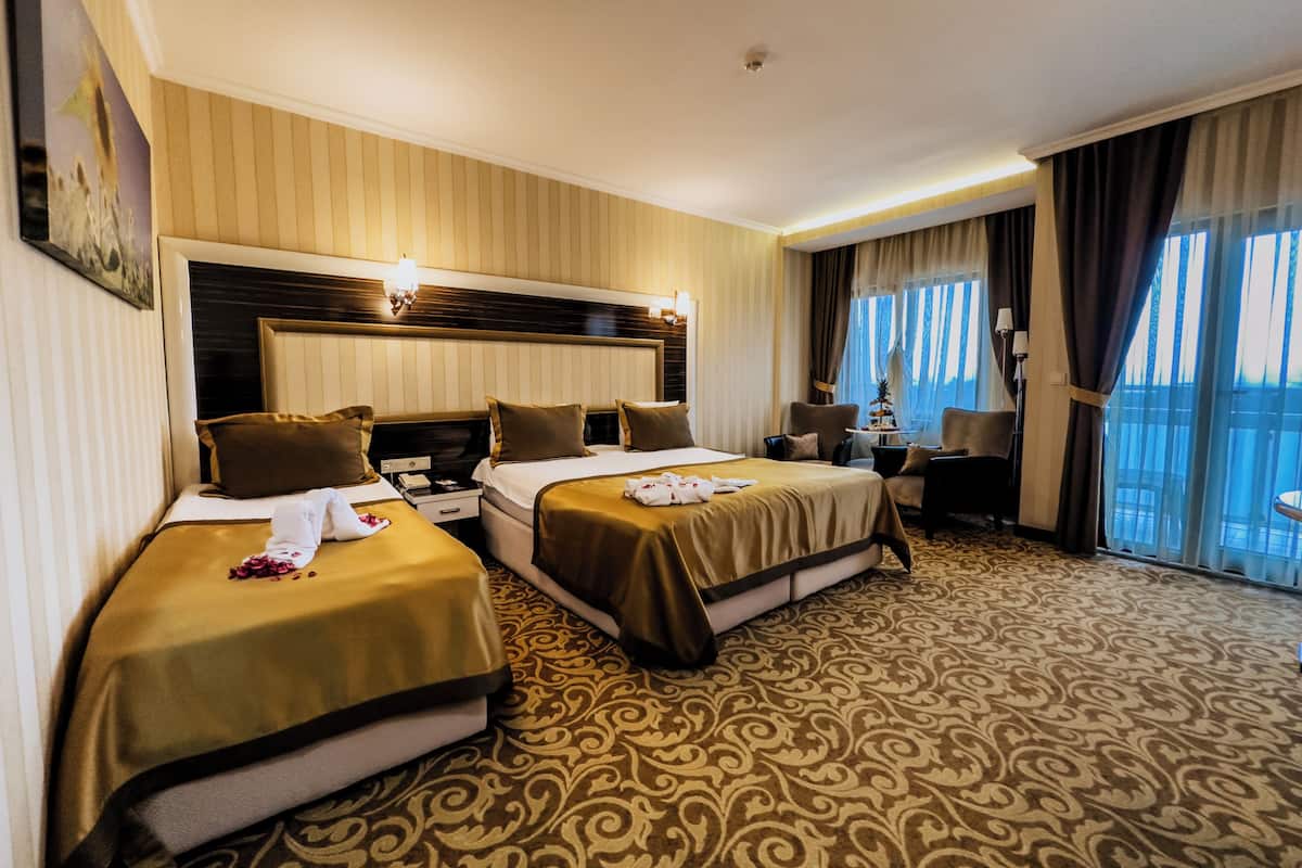 Une chambre d’hôtel avec deux lits, une grande fenêtre, un bureau et une chaise.