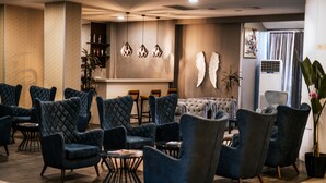 Un vestíbulo moderno con sillones tapizados en azul, una zona de bar y decoración mural.