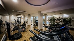 Un gimnasio con cintas de correr, bicicletas estáticas y máquinas de pesas.