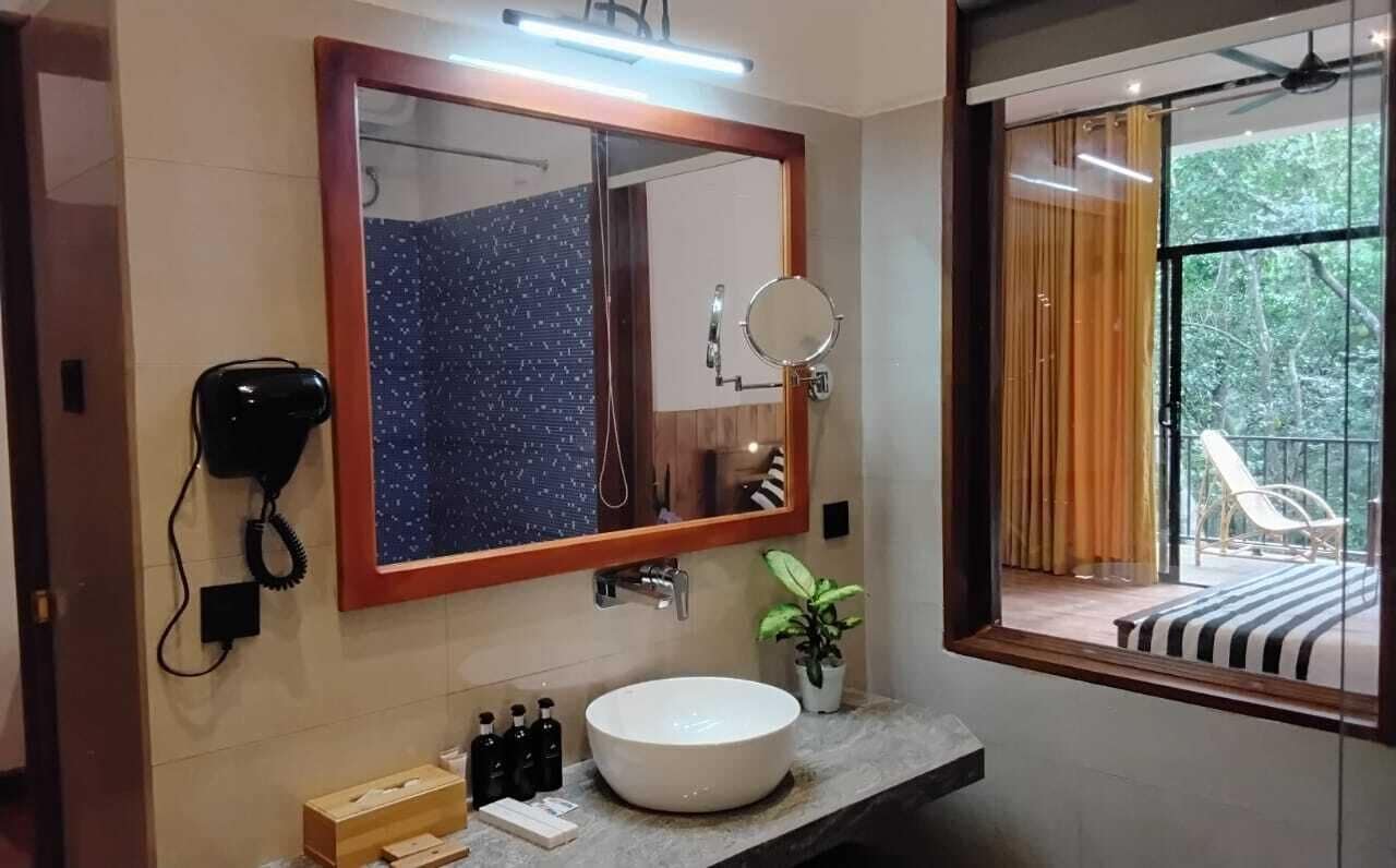 Une salle de bain moderne avec un grand miroir, un miroir rond, un lavabo blanc et un sèche-cheveux.