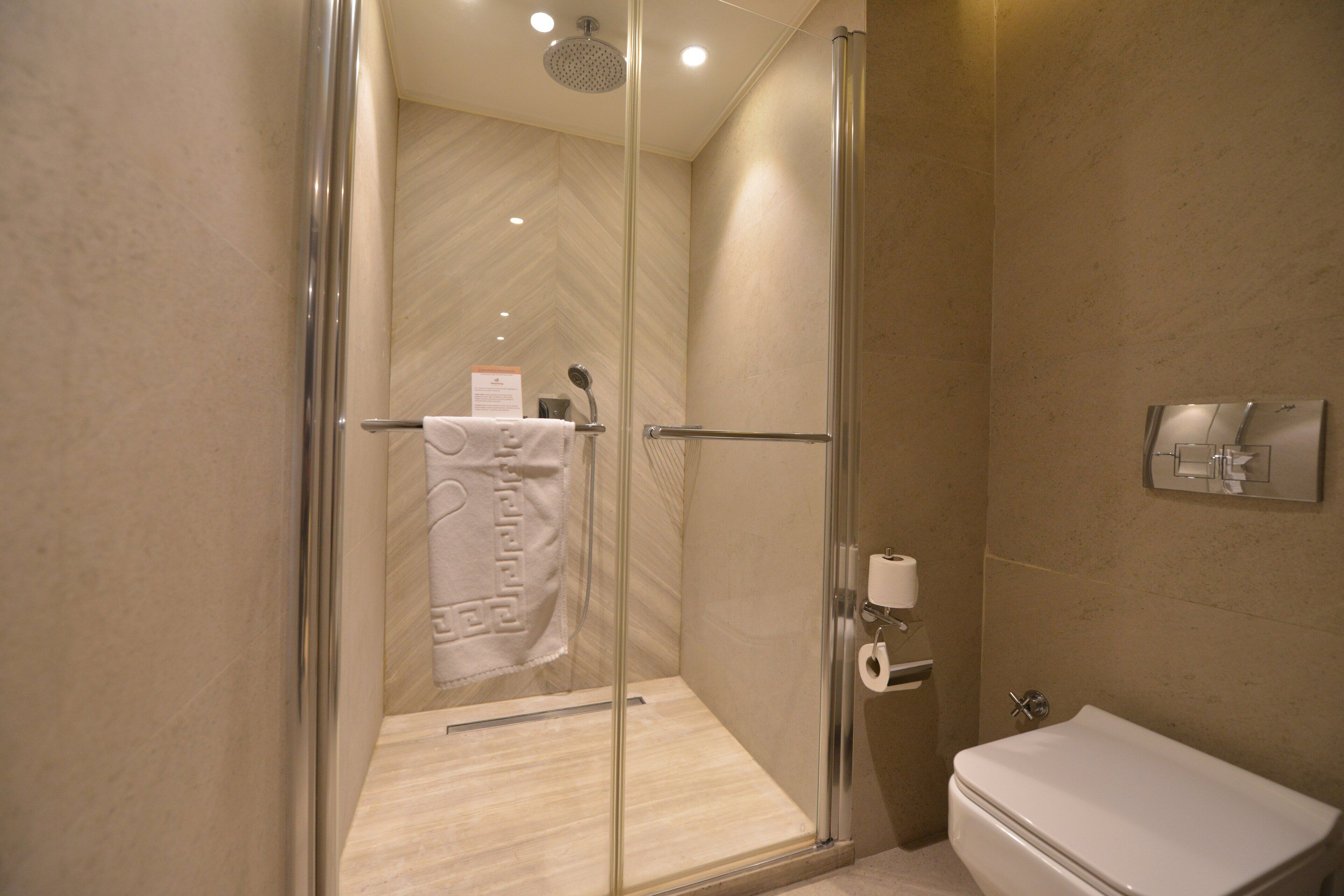 Une salle de bain moderne avec une douche à parois de verre, des toilettes et un porte-serviettes.