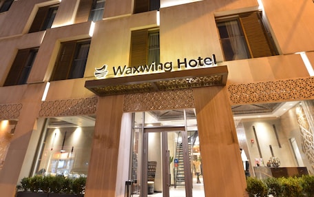 The exterior of the Waxwing Hotel with a modern design, featuring a prominent entrance and a sign above the doors.