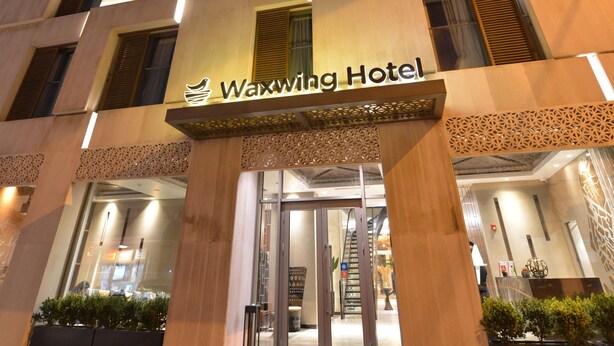 The exterior of the Waxwing Hotel with a modern design, featuring a prominent entrance and a sign above the doors. - Waxwing Hotel (Antakya)