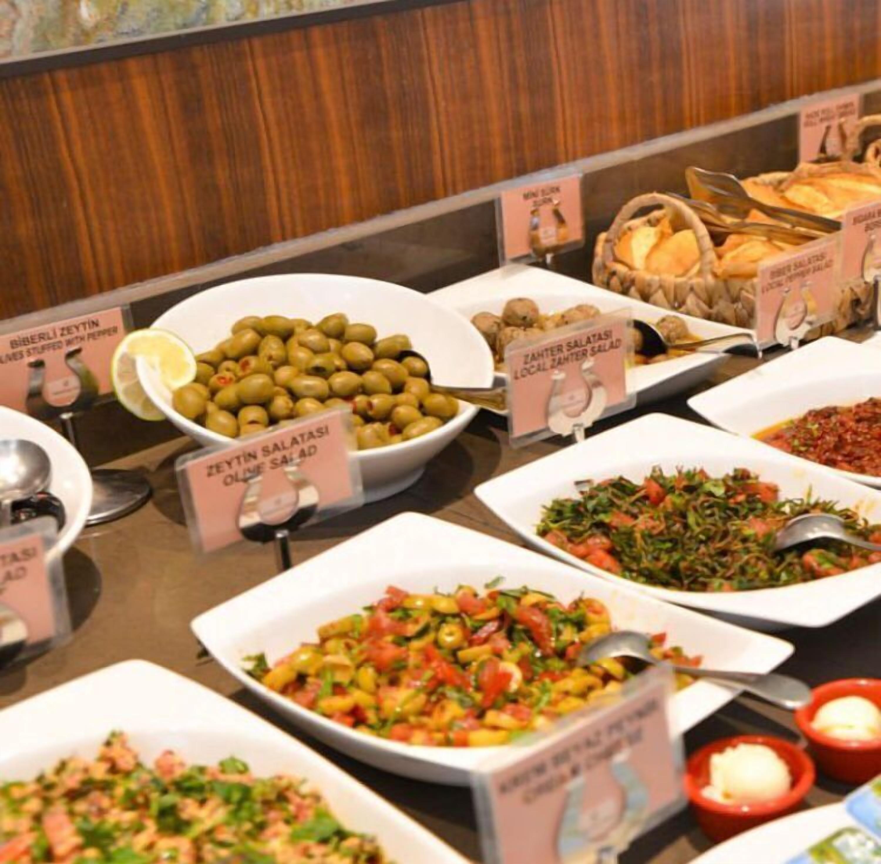 A buffet with various dishes including olives, salads, and bread.